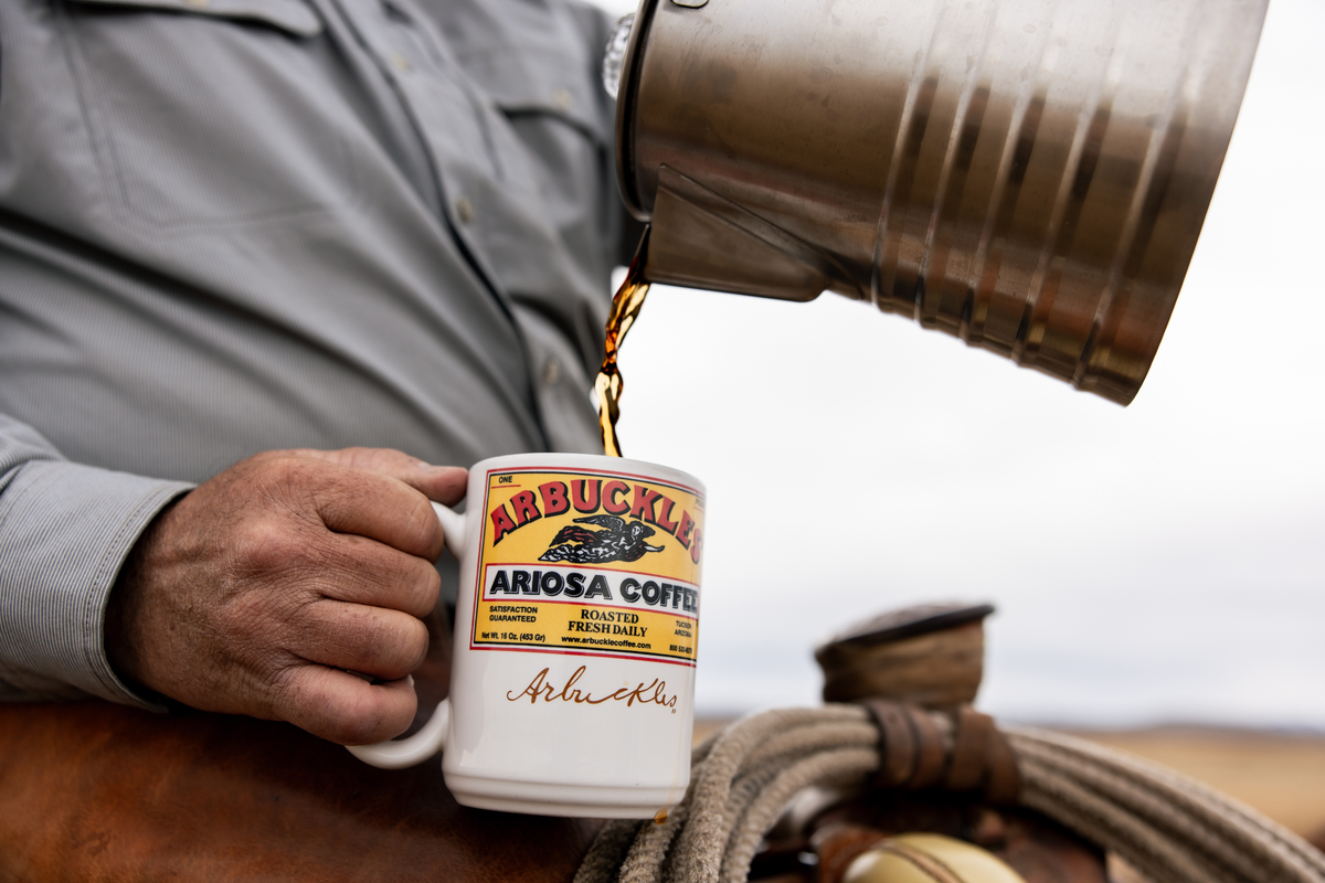 Coffee poured from a camp pot into an Arbuckles' Ariosa mug